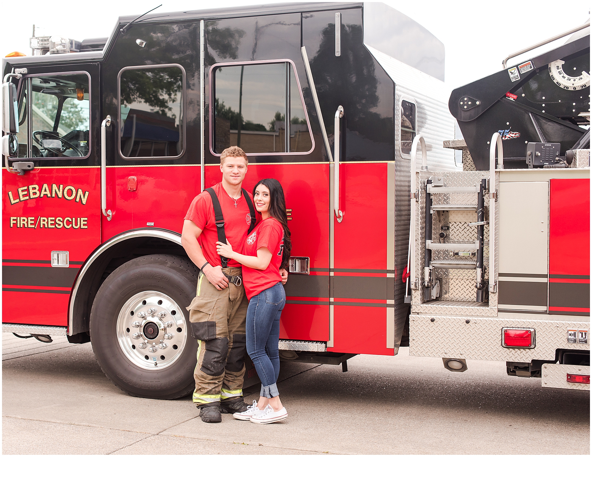 An engaged couple standing in front of a fire engine during their engagement session. Neely Roberts Photography.