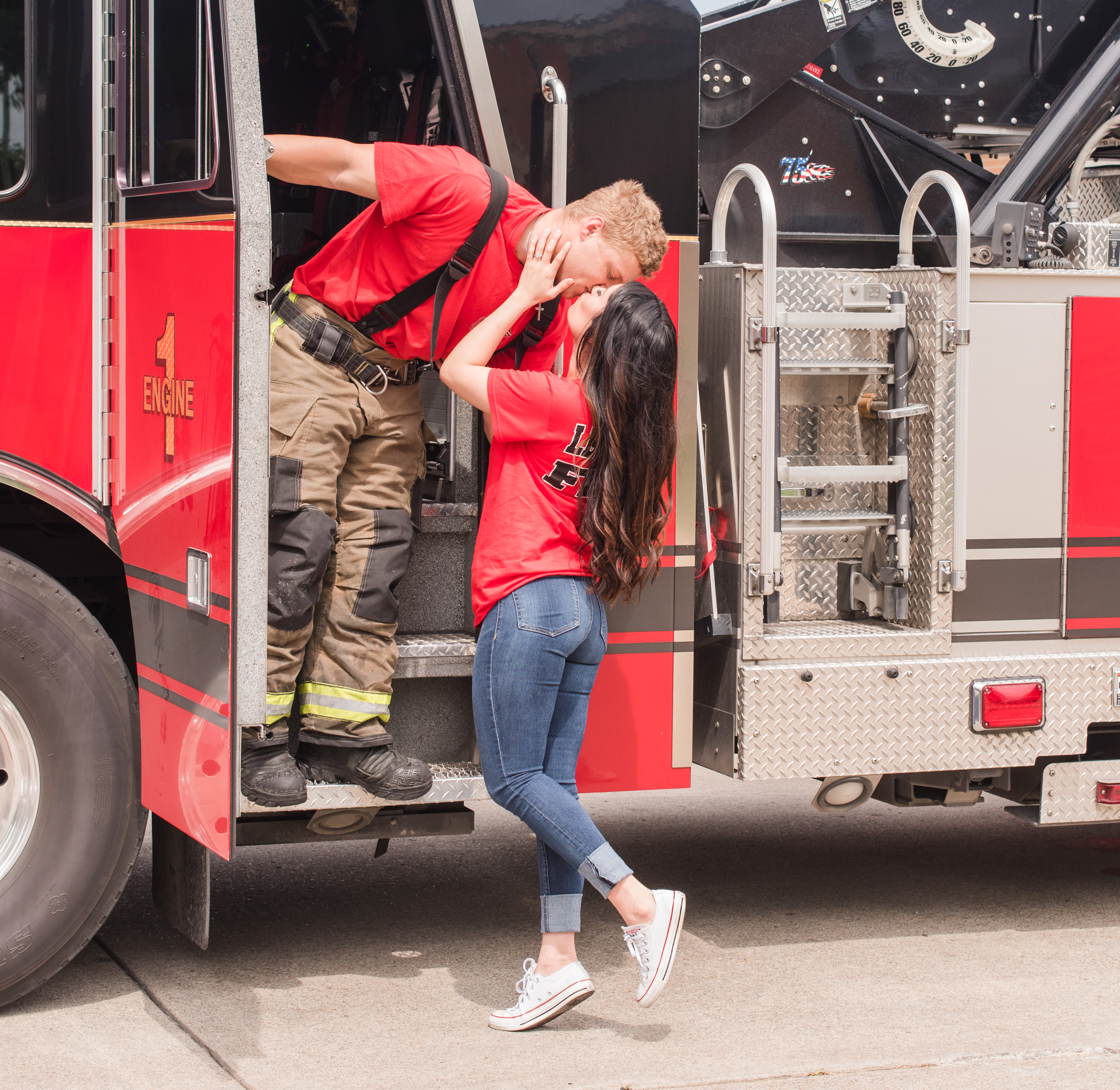 Engaged couple kissing on a fire engine during their engagement session. Neely Roberts Photography.