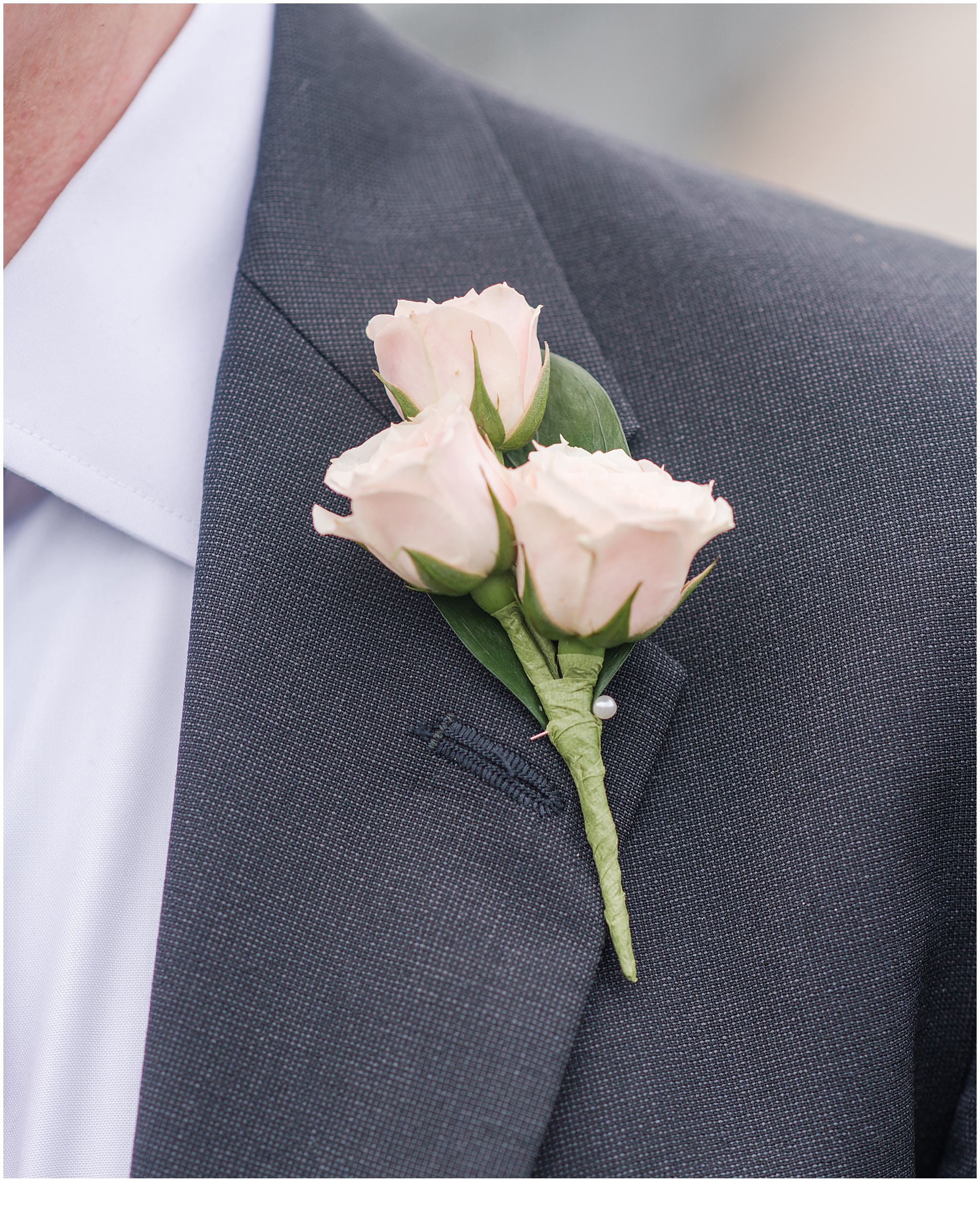 Pink boutonniere pinned on a gray suit.