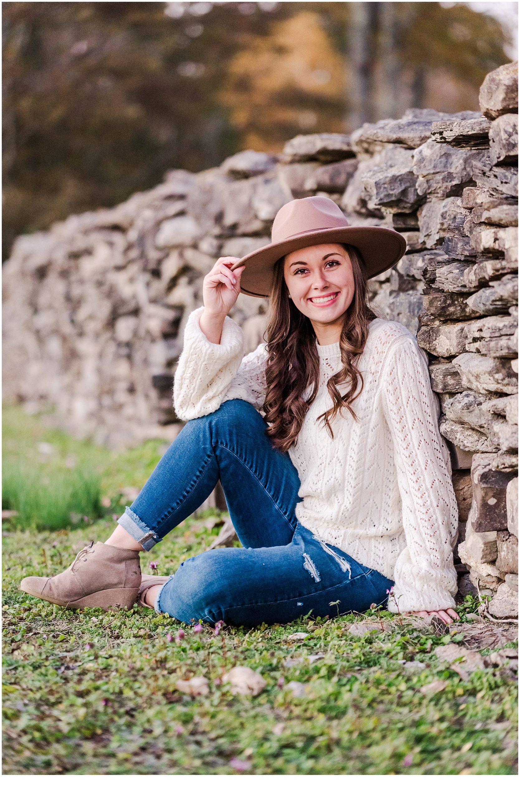Senior girl posing by stone wall at family farm in Middle Tennessee