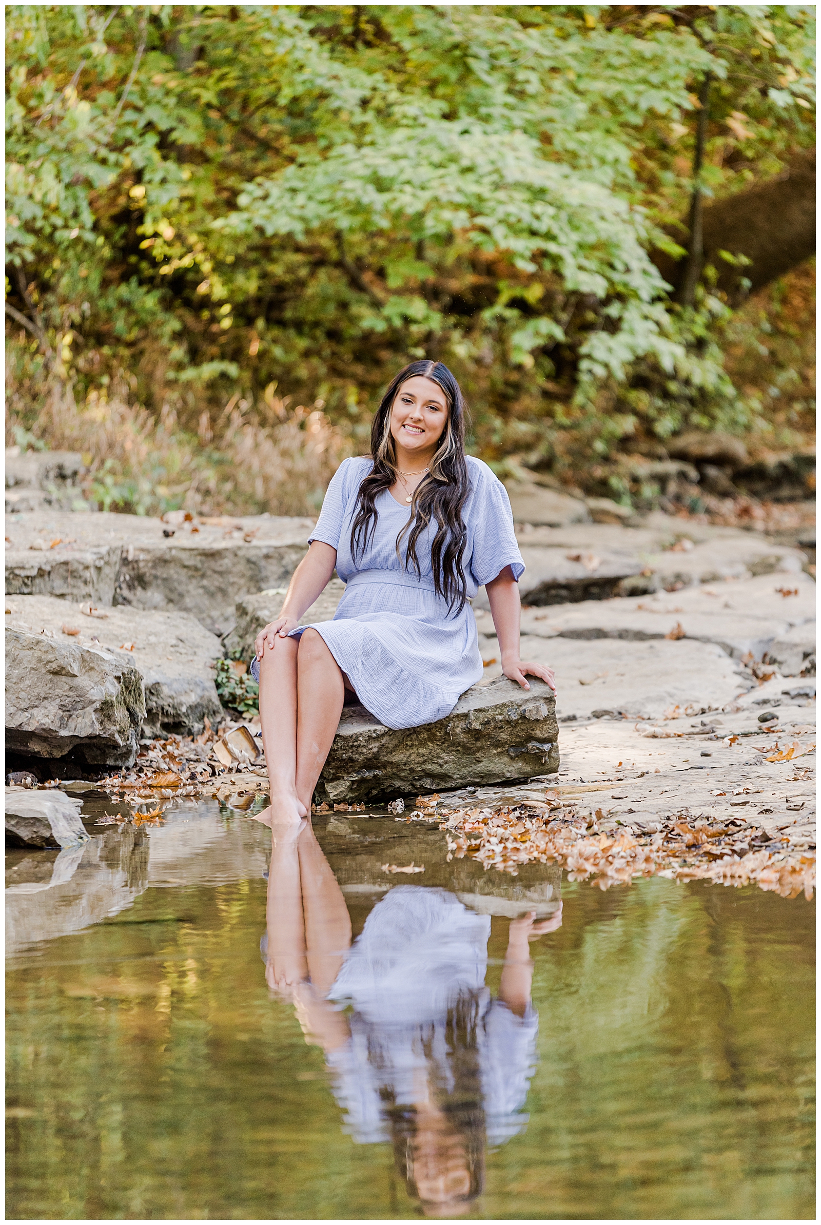 High school senior girl wearing a lavender-colored dress, sitting on the creek bank in Hendersonville, TN