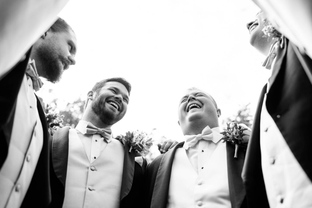 Groom and groomsmen sharing a laugh on a wedding day.