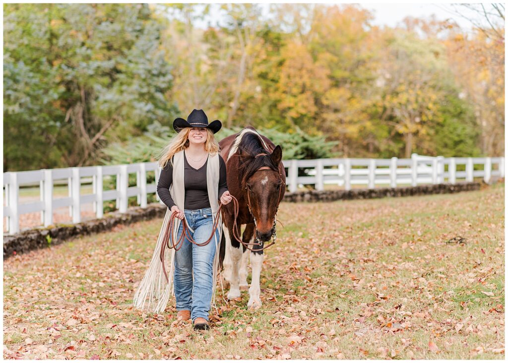 Nashville girl wearing a black cowgirl hat, walking a horse during her Equine Senior Session.