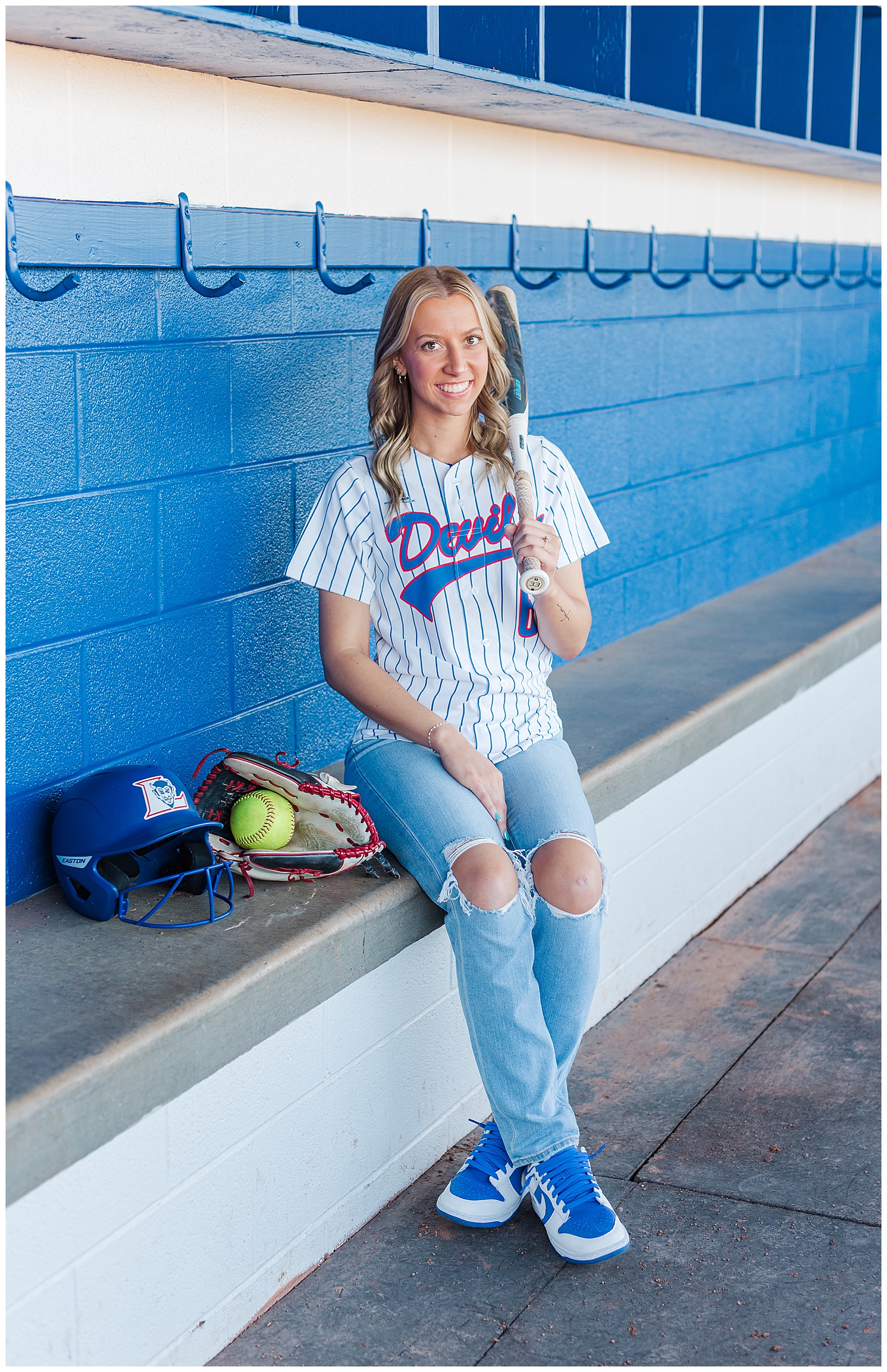 Senior girl sitting in the dugout of her high school softball team. 