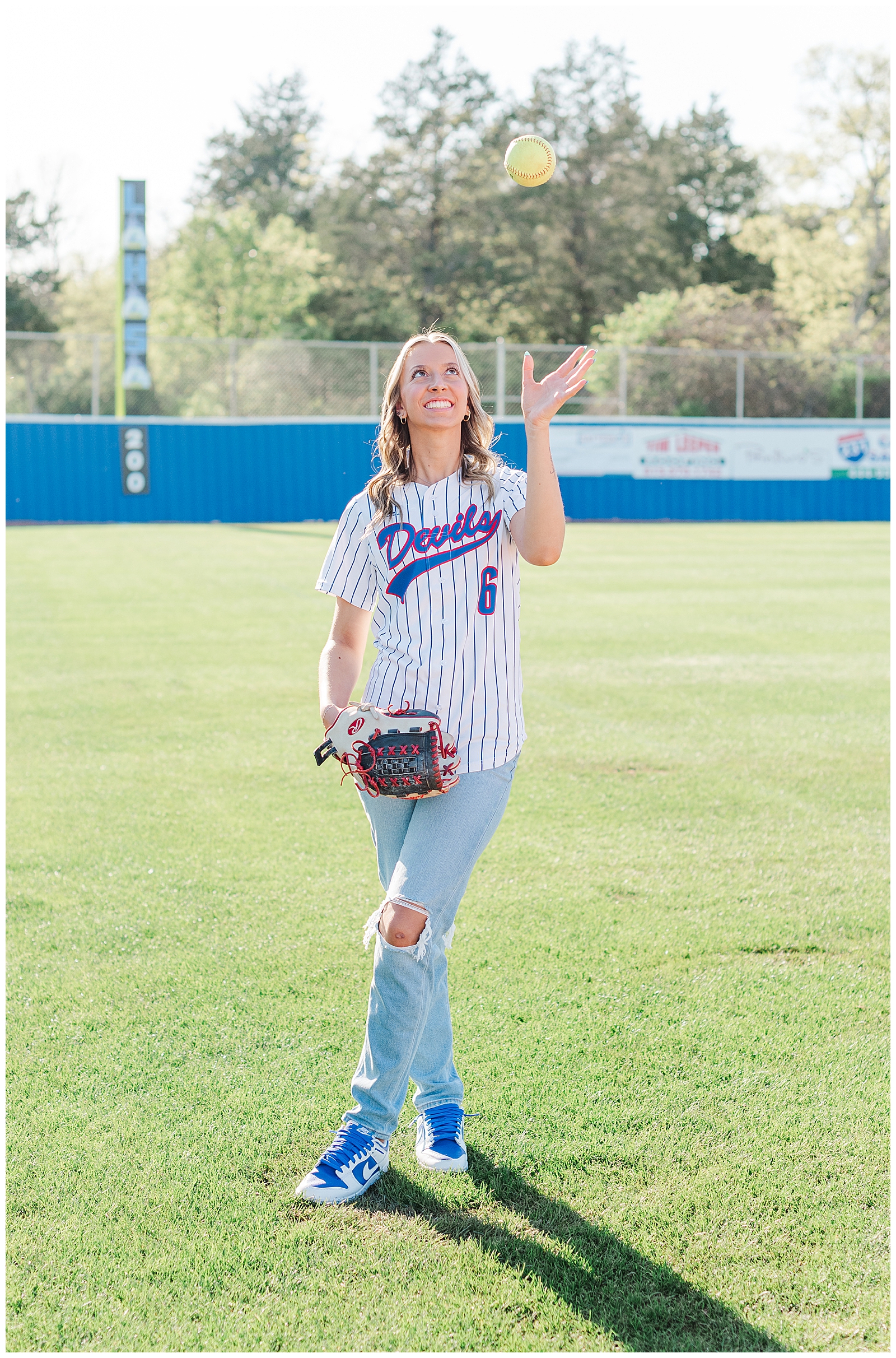Senior girl tossing up a softball on the field at her high school softball field.